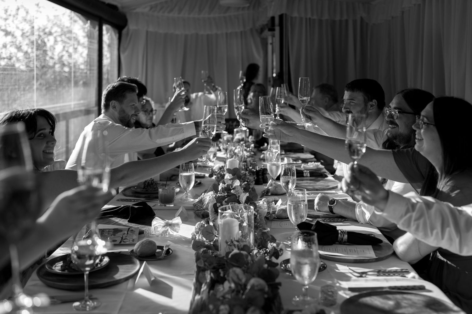 Wedding reception table settings with glassware and decor in dramatic lighting.
