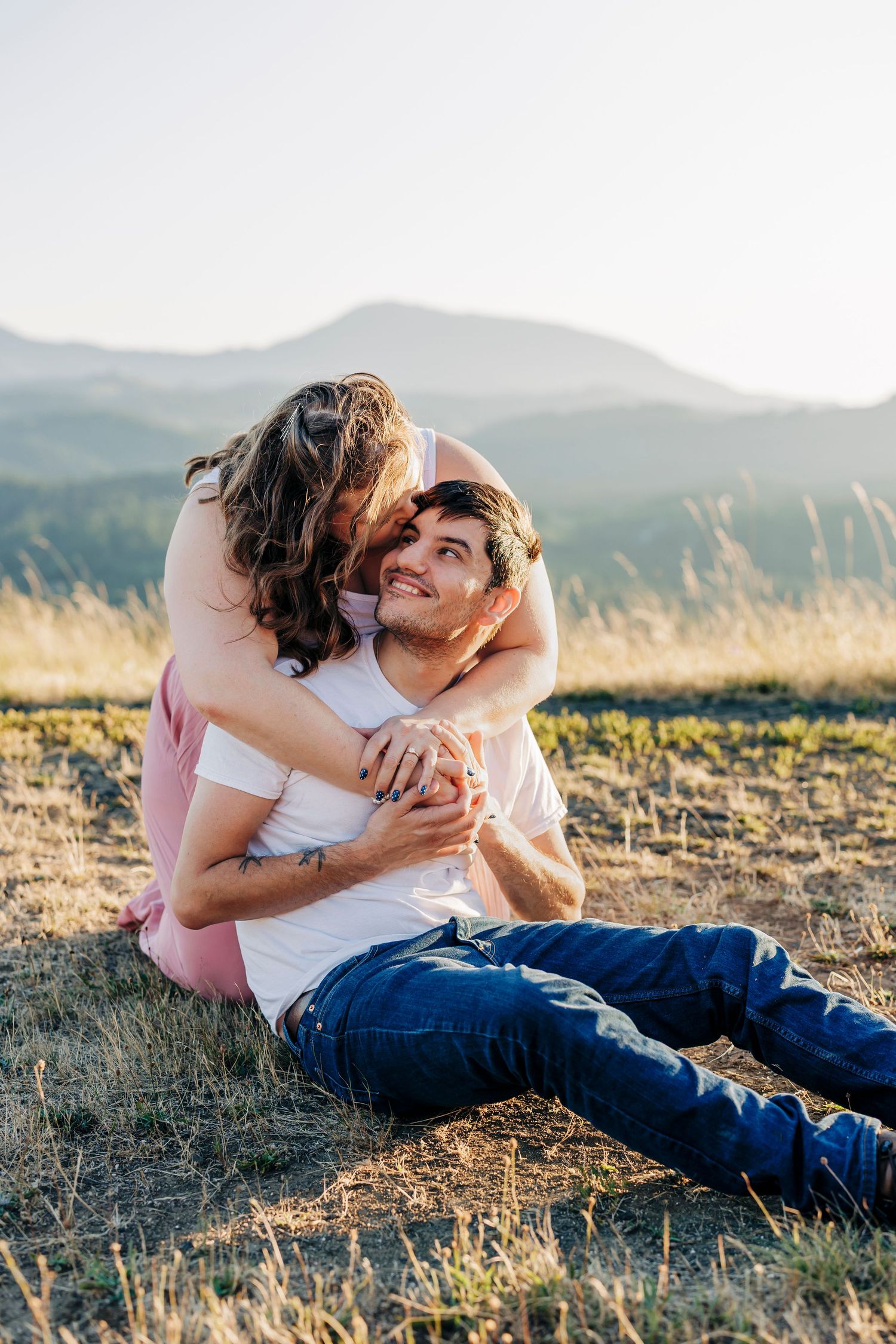 A tender embrace captured in golden light on a mountainside meadow at sunset.