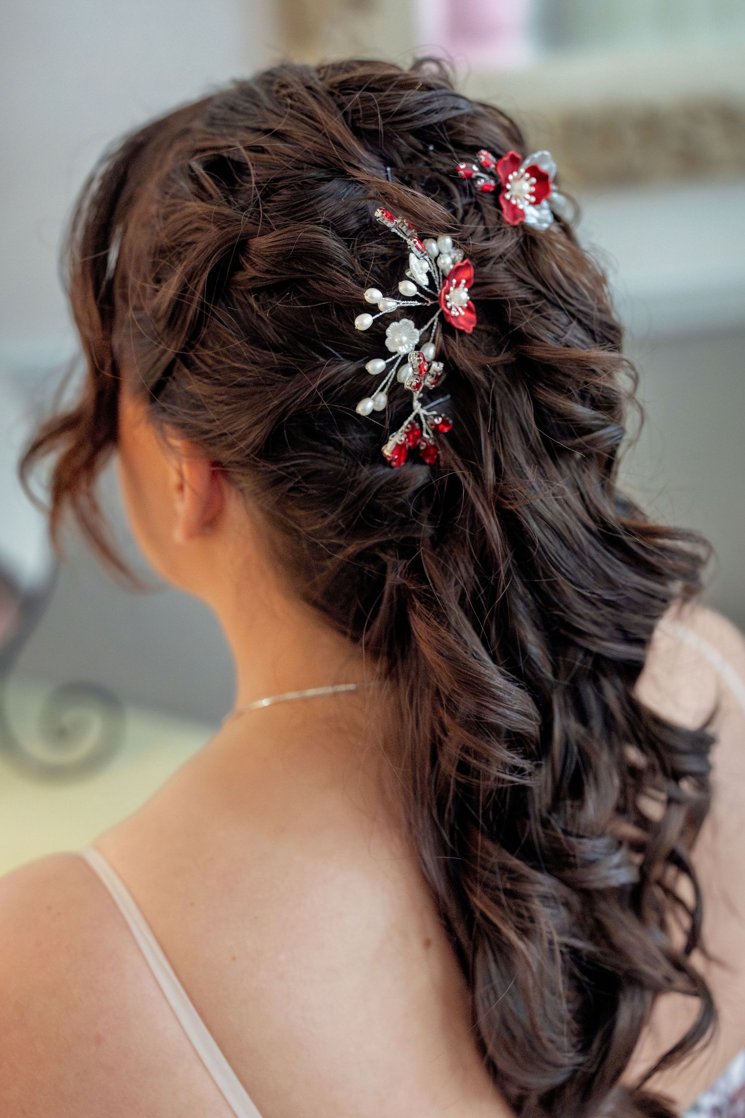 Elegant bridal hairstyle adorned with red and silver floral hair accessories.