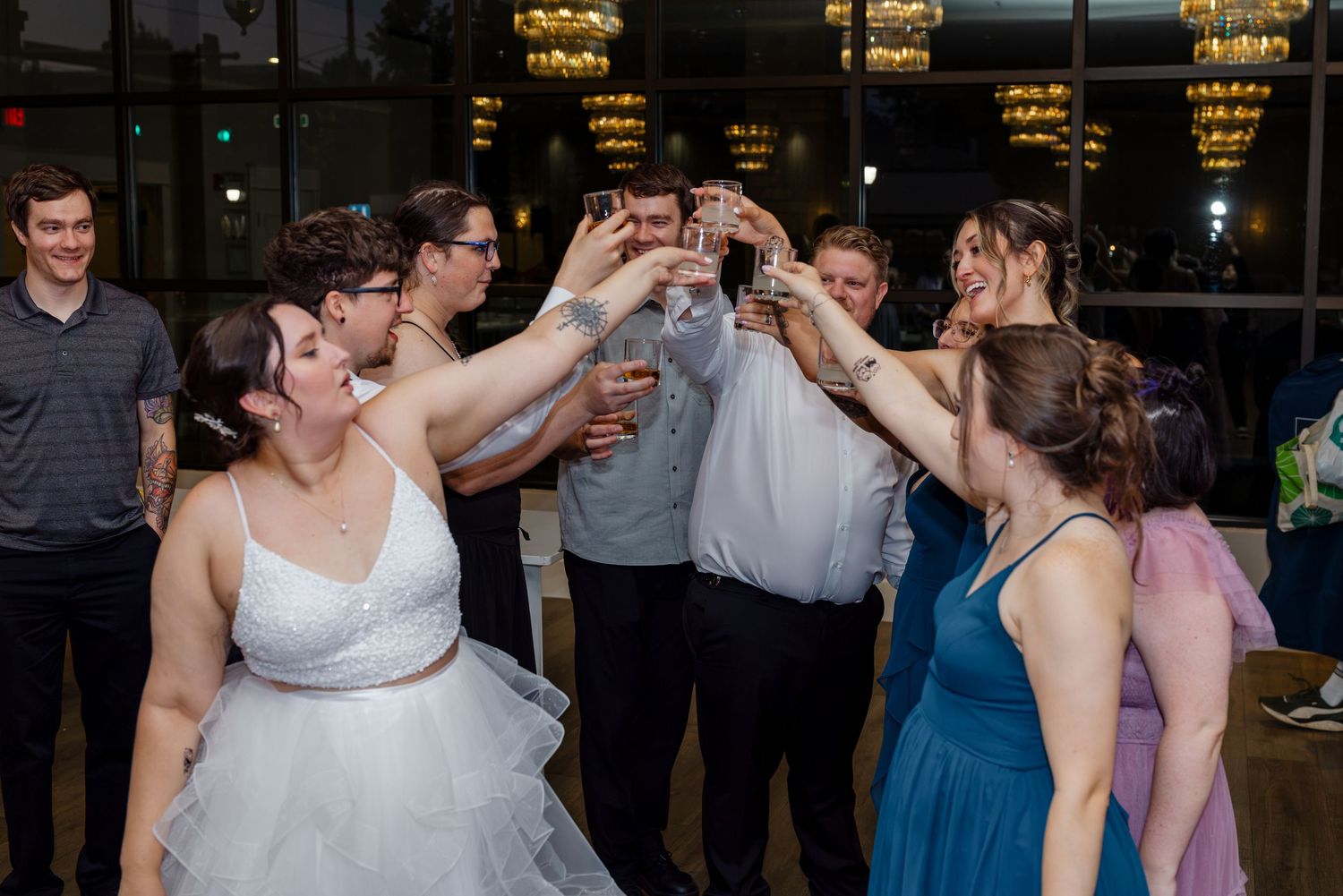 Wedding guests raising glasses in a joyful toast on the dance floor at the reception.