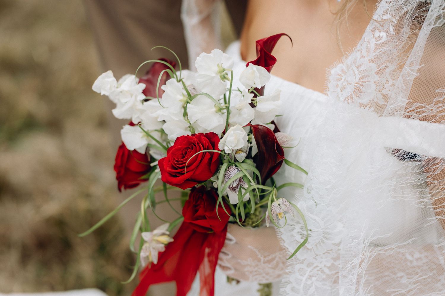 Wedding bouquet details featuring deep red roses and white flowers with delicate lace accents.