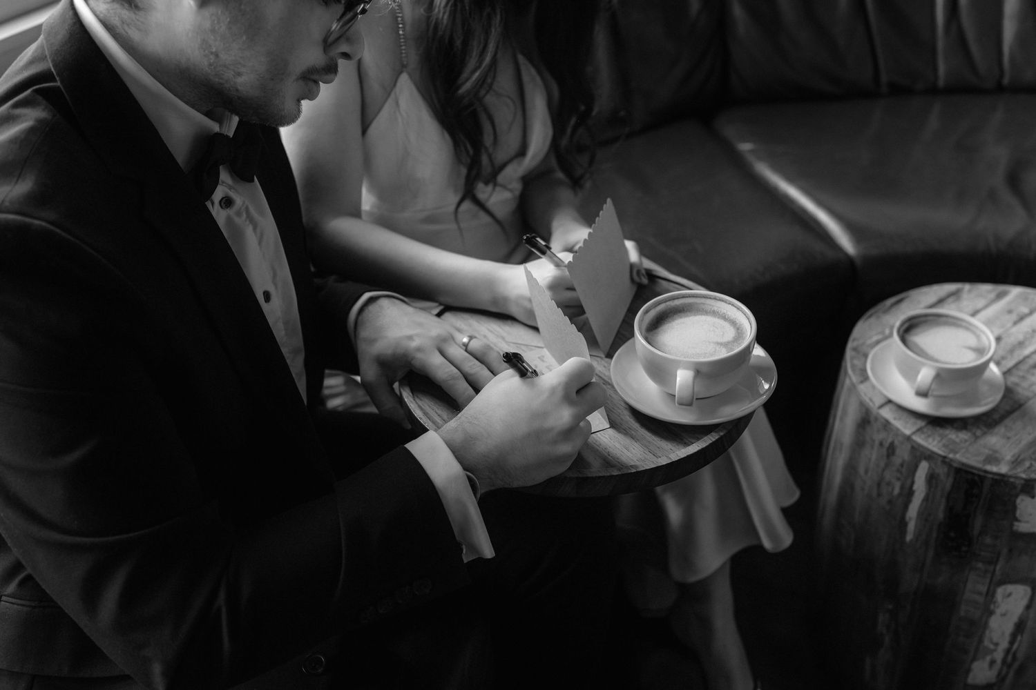 Black and white intimate moment with coffee cups and formal attire.