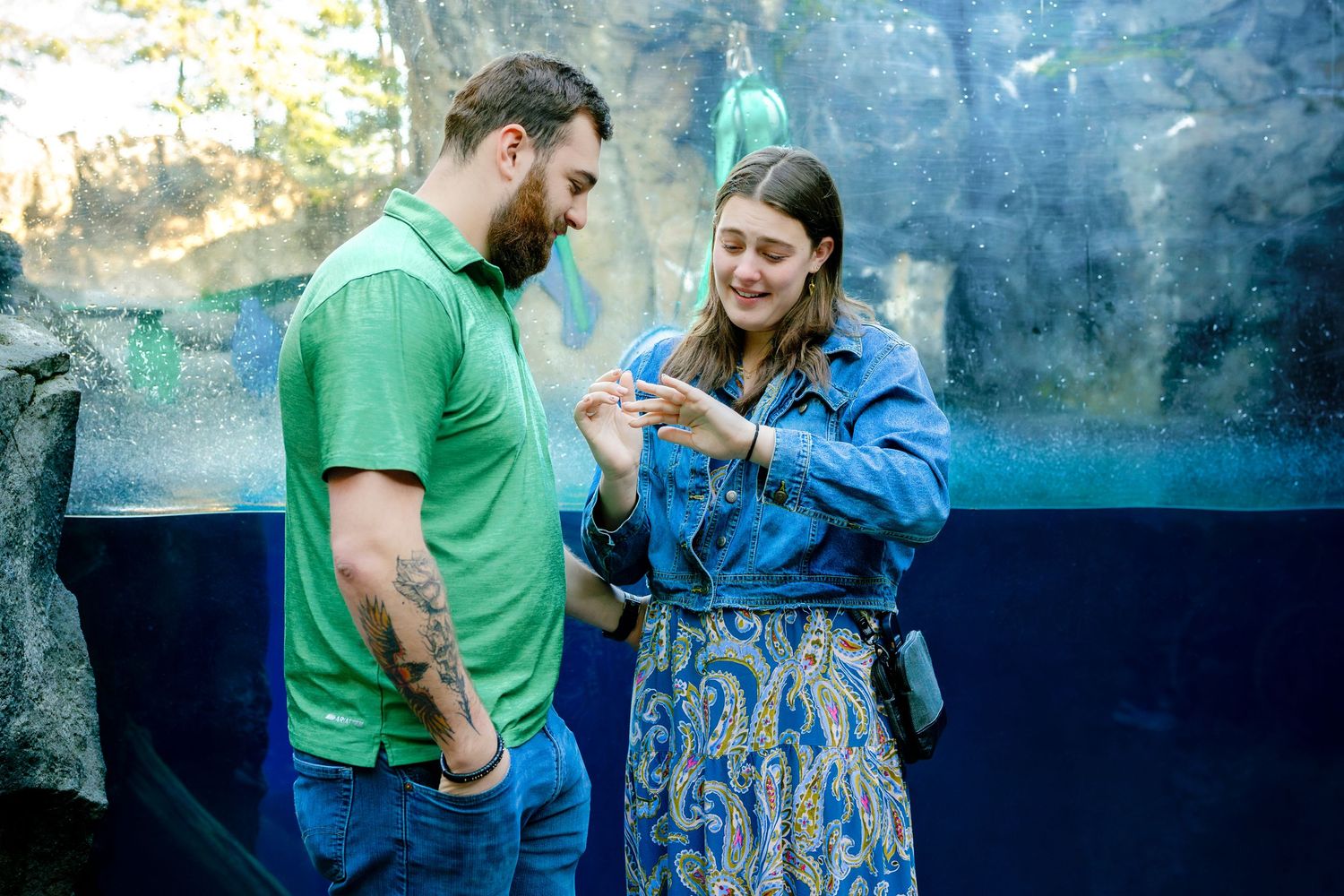 Couple shares a romantic moment by aquarium display with blue lighting.