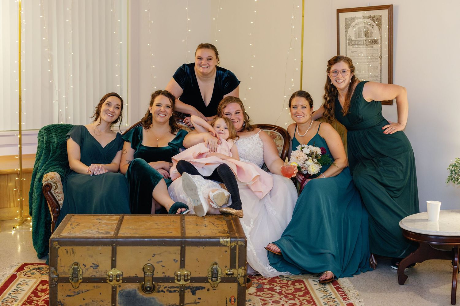 Wedding party relaxing and posing on vintage leather couch during reception.