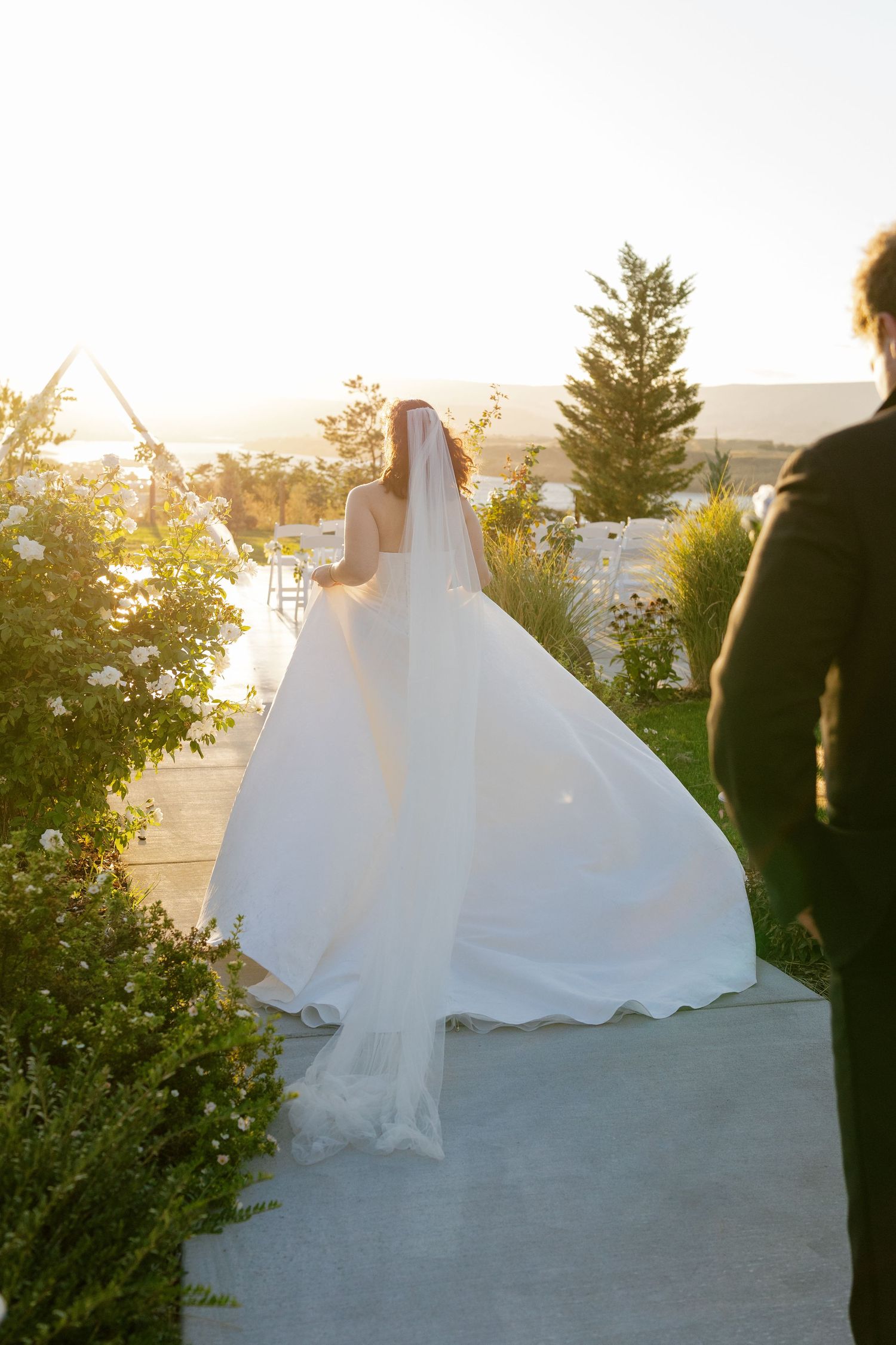 A flowing white wedding dress billows in the breeze against a scenic mountain backdrop.