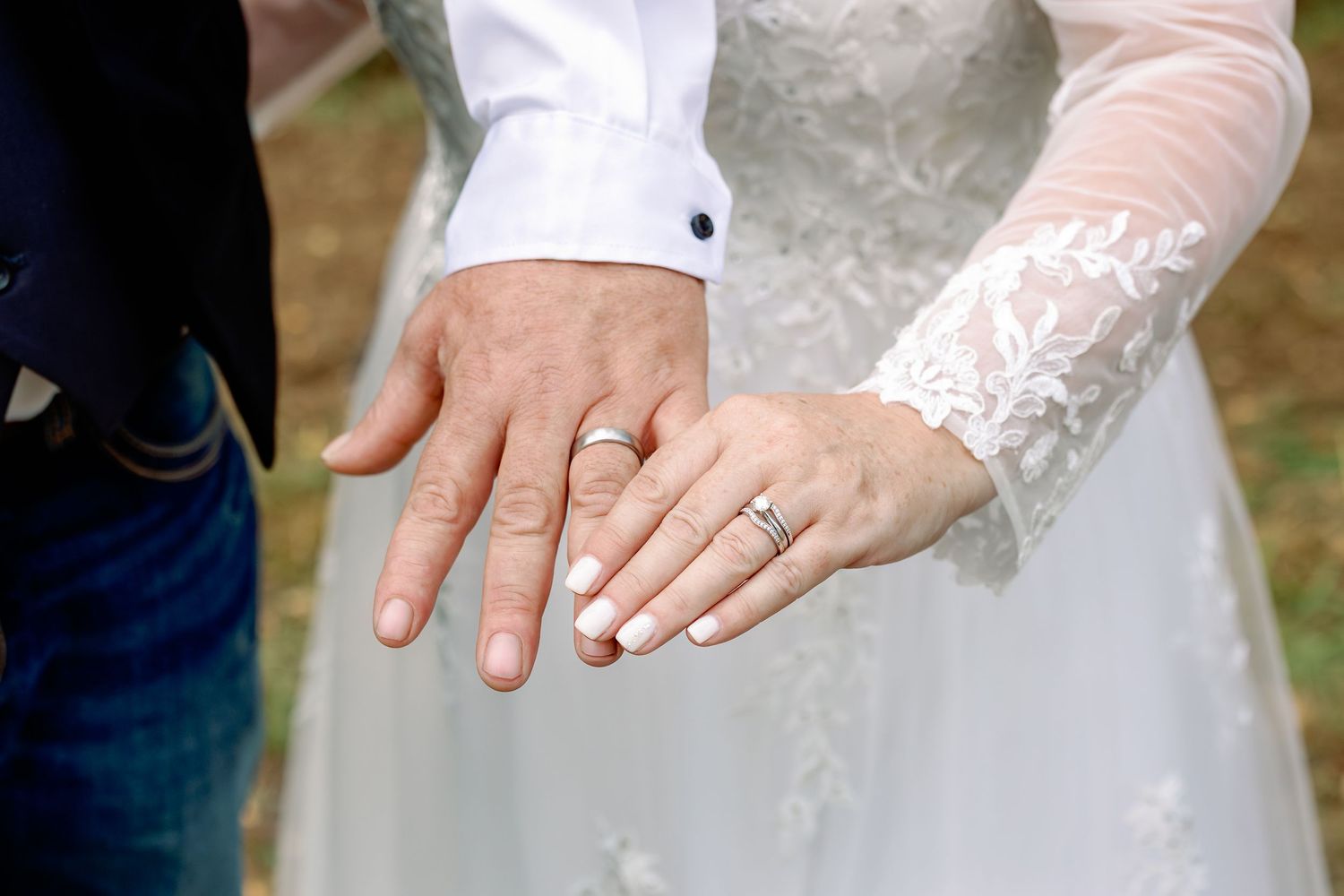Close-up detail shots of hands wearing wedding rings on a white lace dress background.