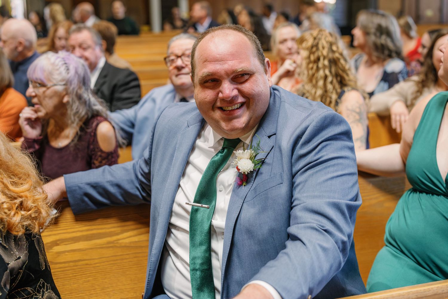 Wedding guests share joyful laughter during a reception celebration in a church hall.