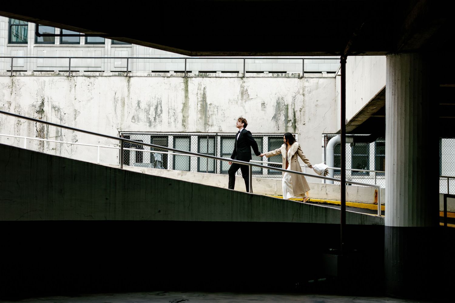 A silhouetted couple walking through an urban tunnel or passageway.