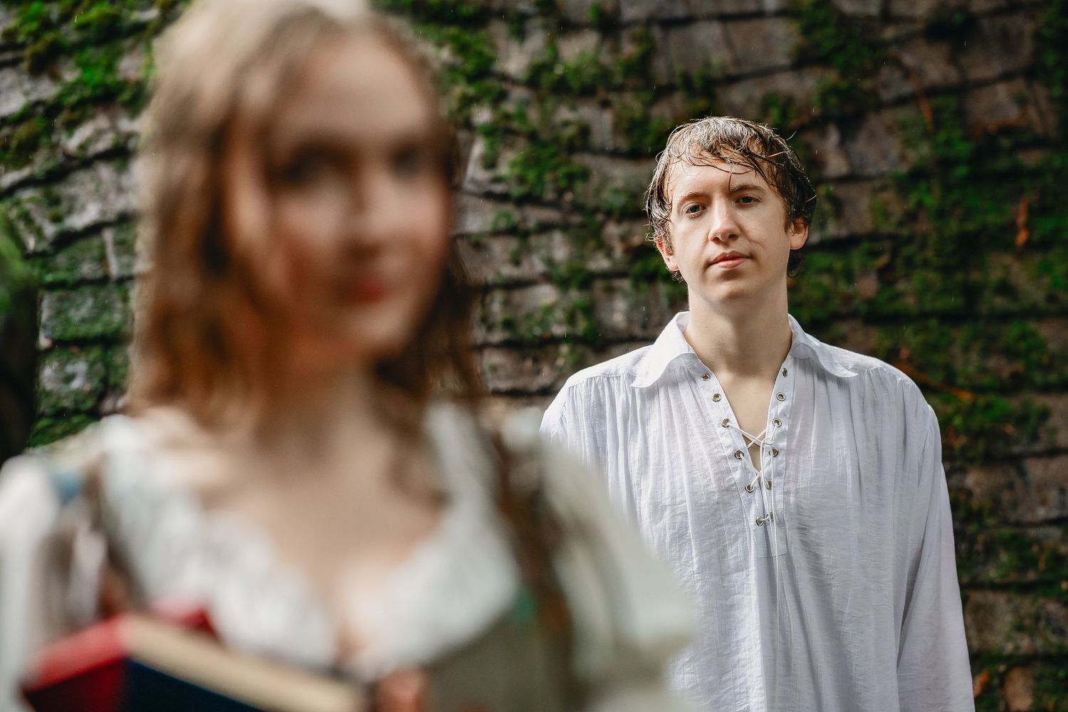 An intimate moment captured against a rustic brick wall background in soft focus.