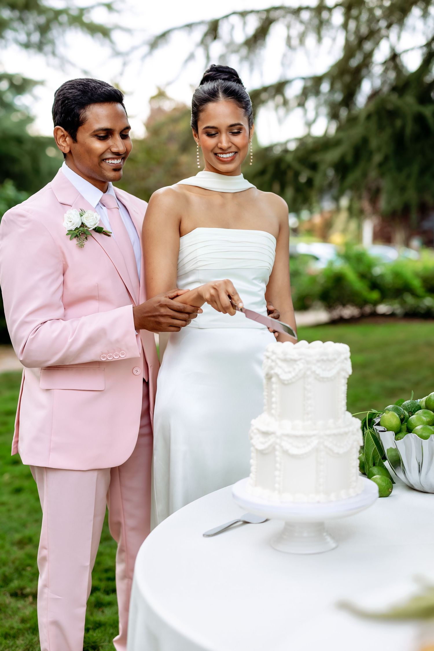 Couple cutting their white wedding cake at an outdoor reception.