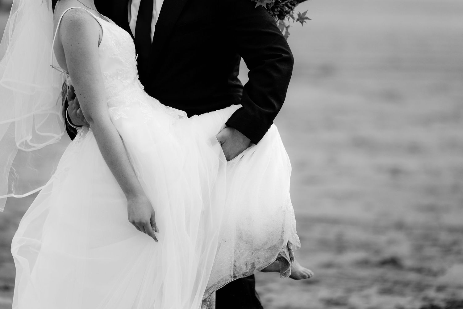 A romantic black and white wedding photo shows a couple's hands clasped together in an intimate moment.