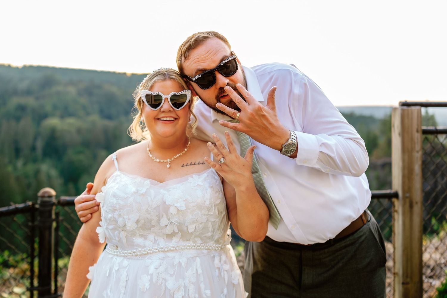 A happy couple in wedding attire shares a romantic dance together outdoors with scenic mountain views in the background.