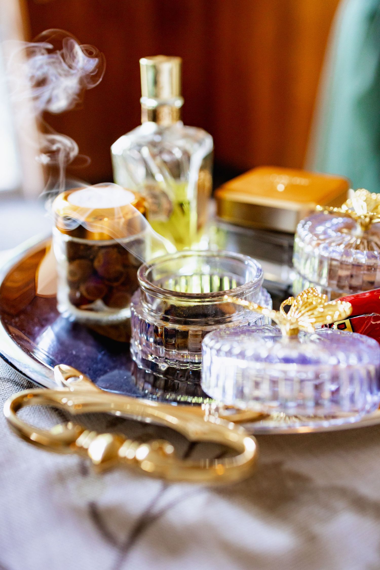 Elegant table setting with perfume bottles, crystal dishes, and golden decorative elements with wisps of smoke.