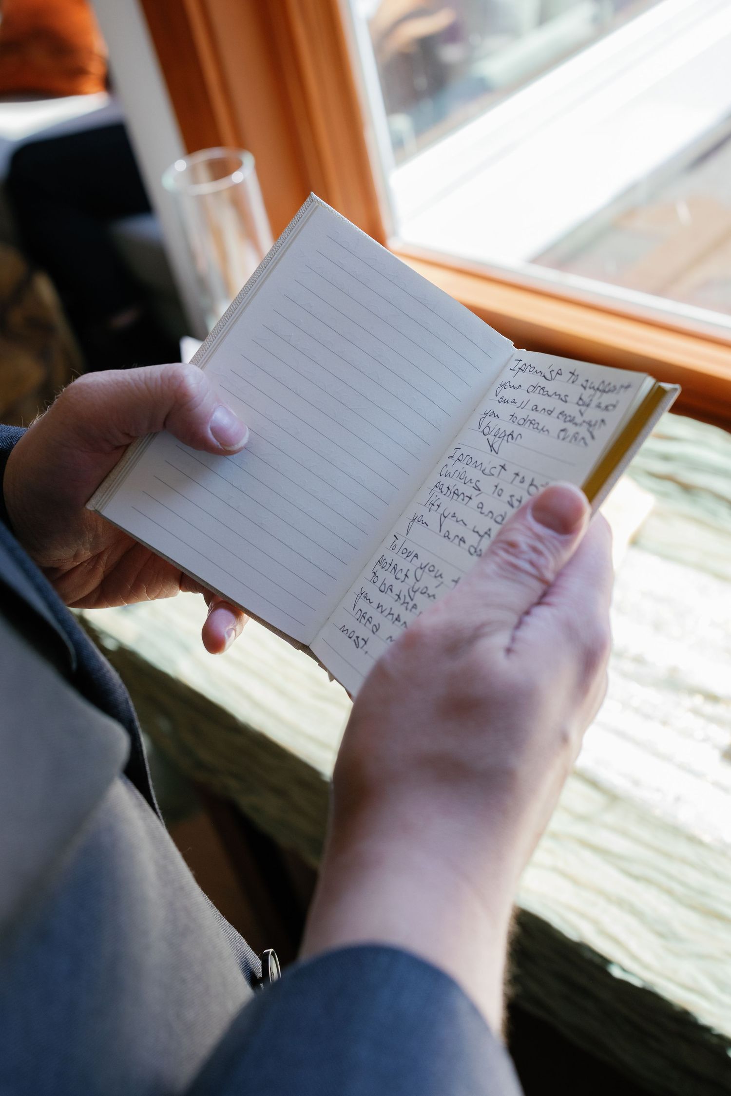 Hands holding and reading handwritten notes or cards in natural window light.