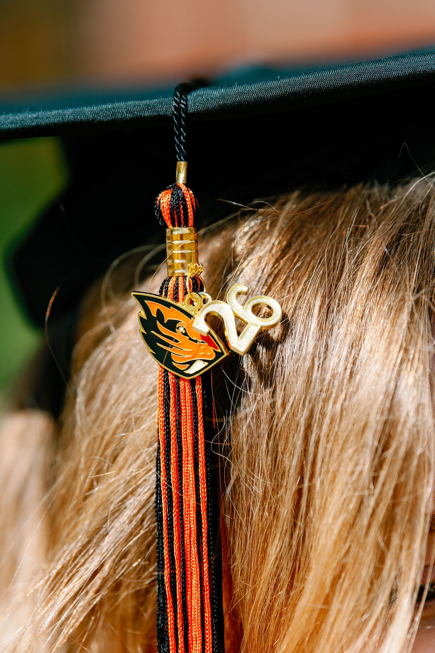 Close-up of Oregon State University graduation cap tassel with Beavers logo charm and gold 28 year charm.
