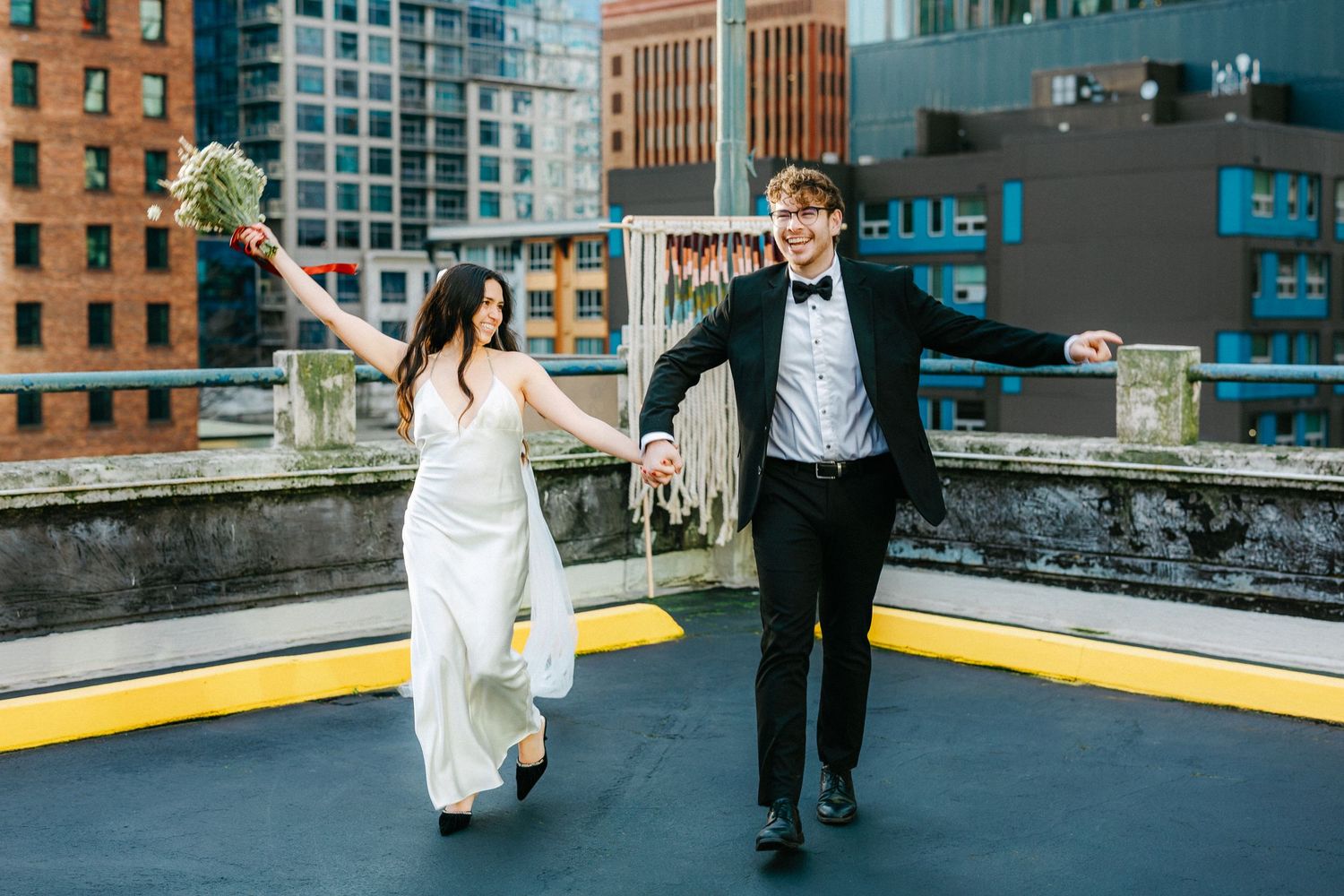 Couple dancing and twirling on rooftop with Seattle architecture in background.
