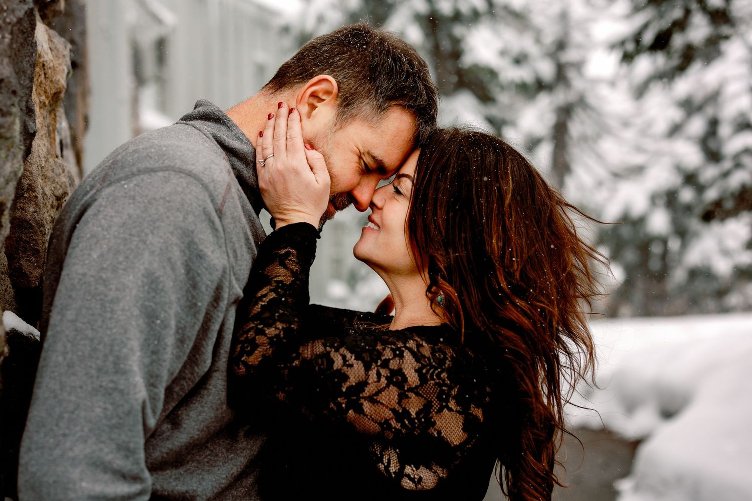 A couple shares intimate romantic moments in a snowy winter forest setting.