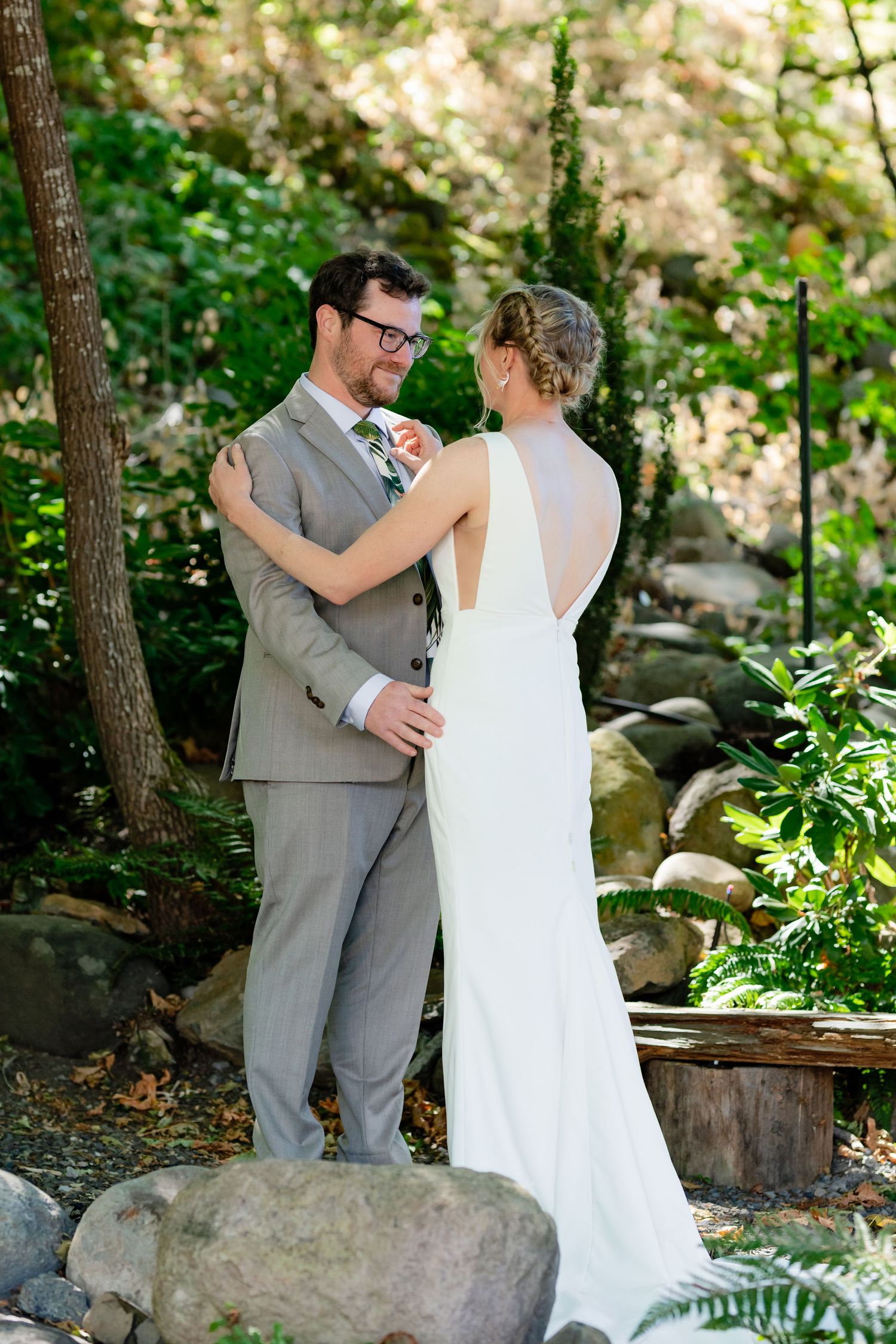 Bride and groom share a romantic first look moment surrounded by lush greenery at an outdoor wedding venue.