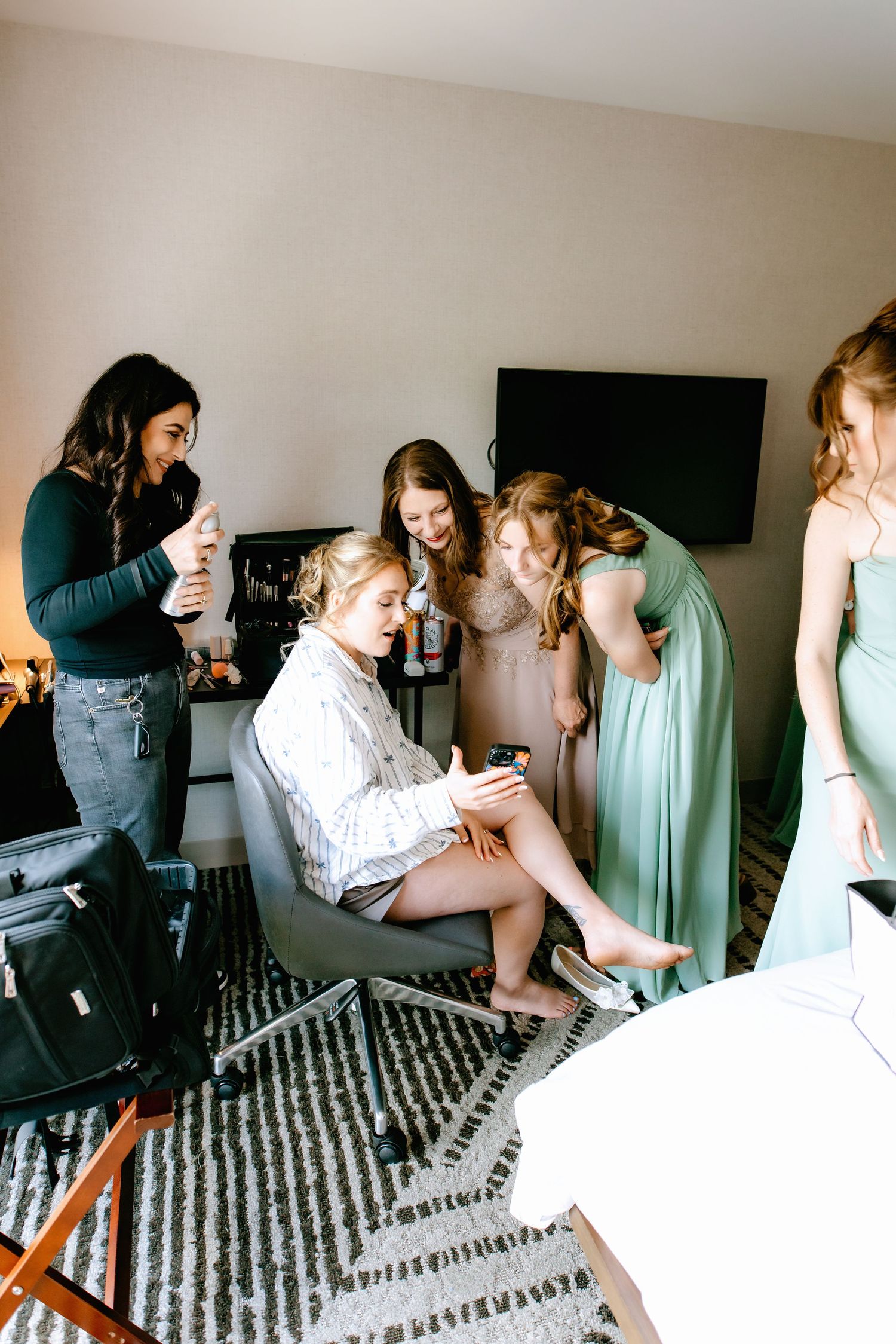 Bridesmaids help bride get ready in hotel room before wedding ceremony.