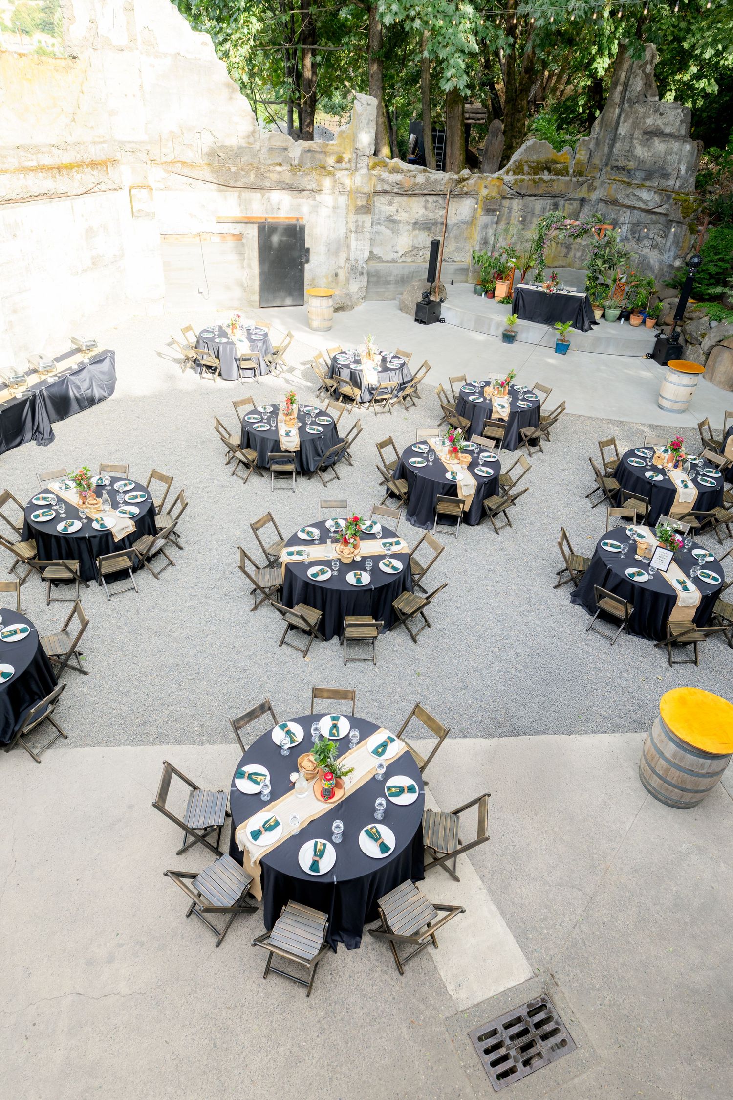 Aerial view of elegant outdoor wedding reception with round tables, navy linens, and wooden chairs.