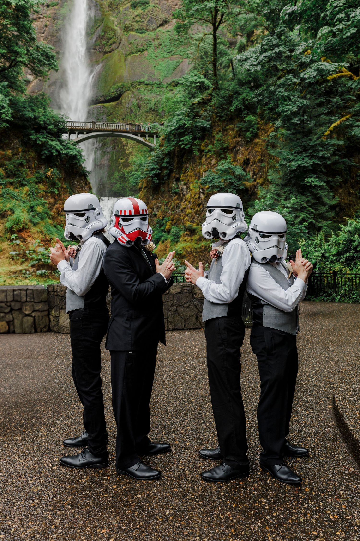 Groomsmen in Star Wars Stormtrooper helmets pose playfully at Multnomah Falls.