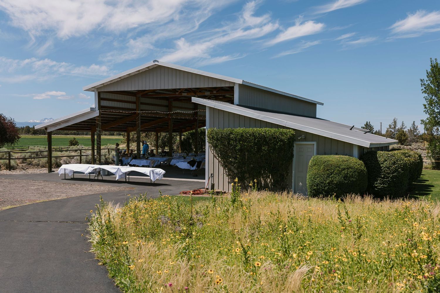Rural venue exterior buildings and parking area under blue skies with scattered clouds.