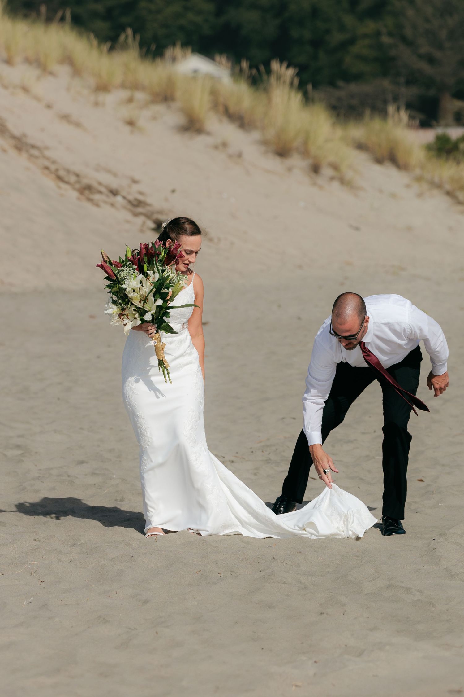 Wedding couple playing in the sand during a beach photoshoot.