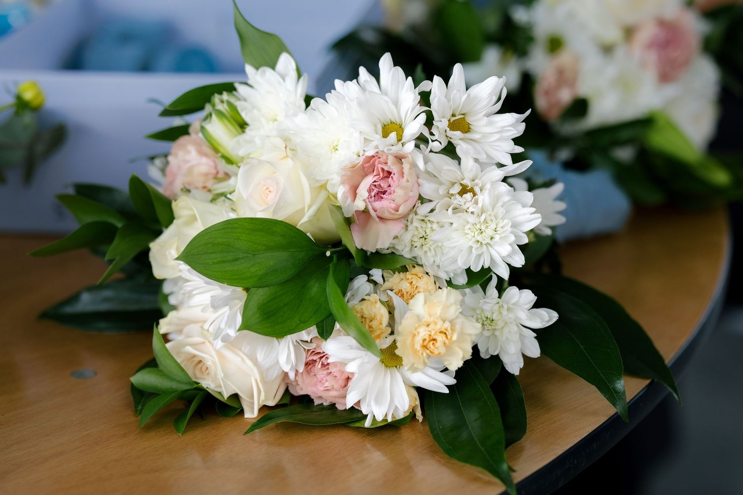 Fresh white daisies and pink roses arranged with greenery on a dark surface.