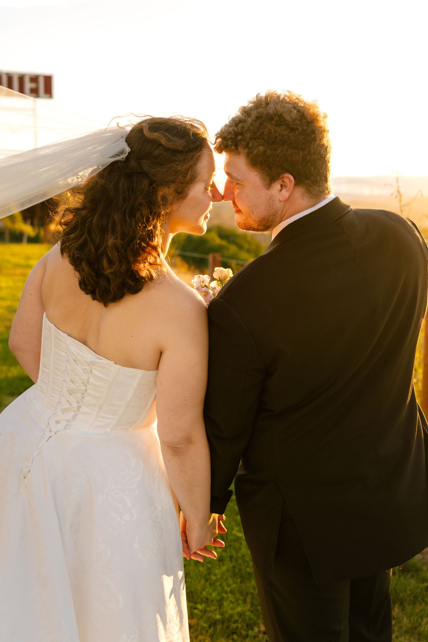 Romantic sunset portrait showing back view of couple in wedding attire.