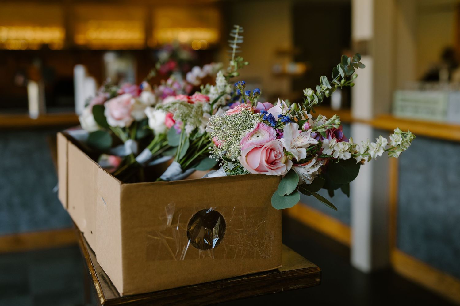 Wooden box filled with pink and white floral bouquets featuring roses and eucalyptus for a wedding ceremony.