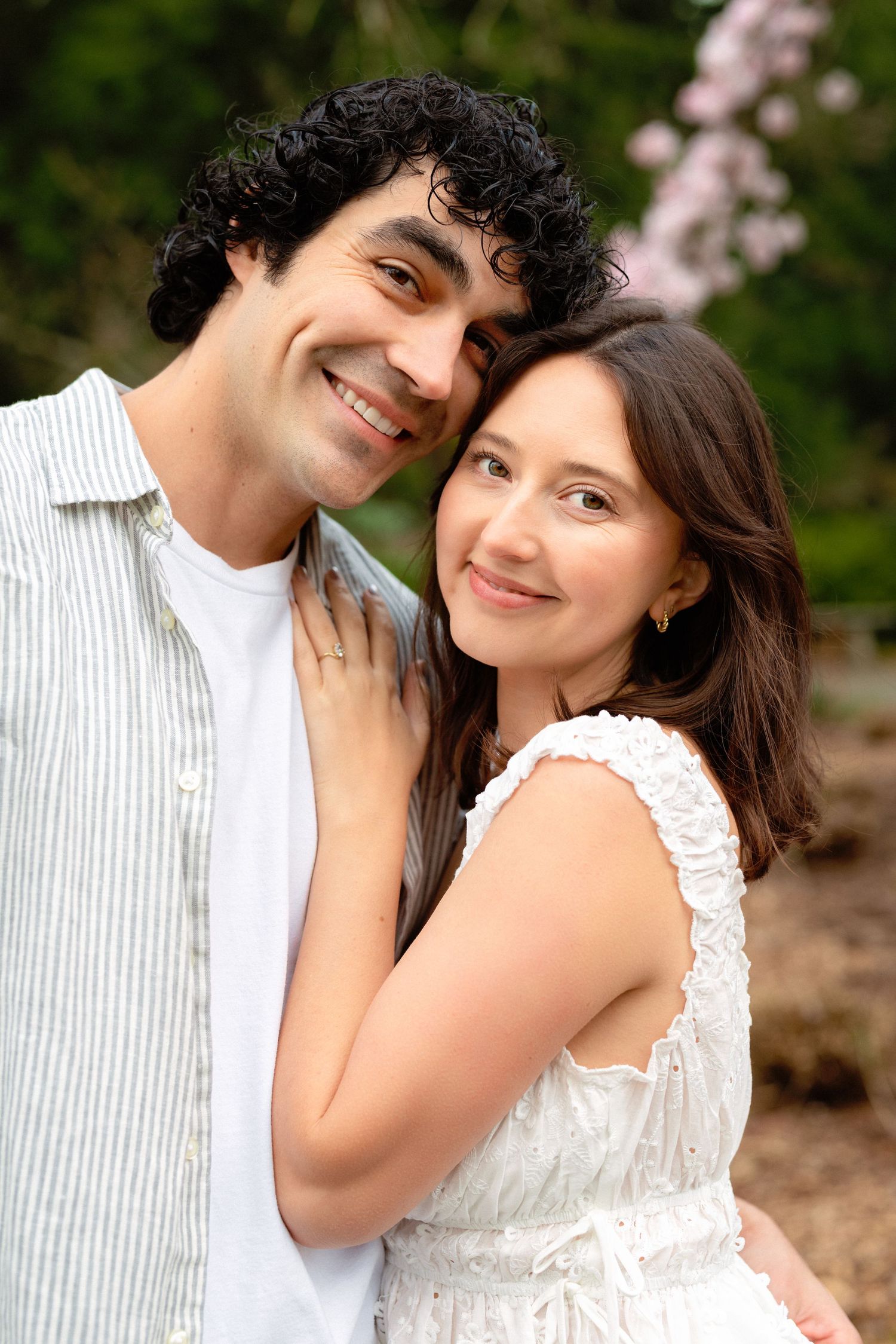 A tender moment captured between a couple in white and striped clothing against a natural backdrop.