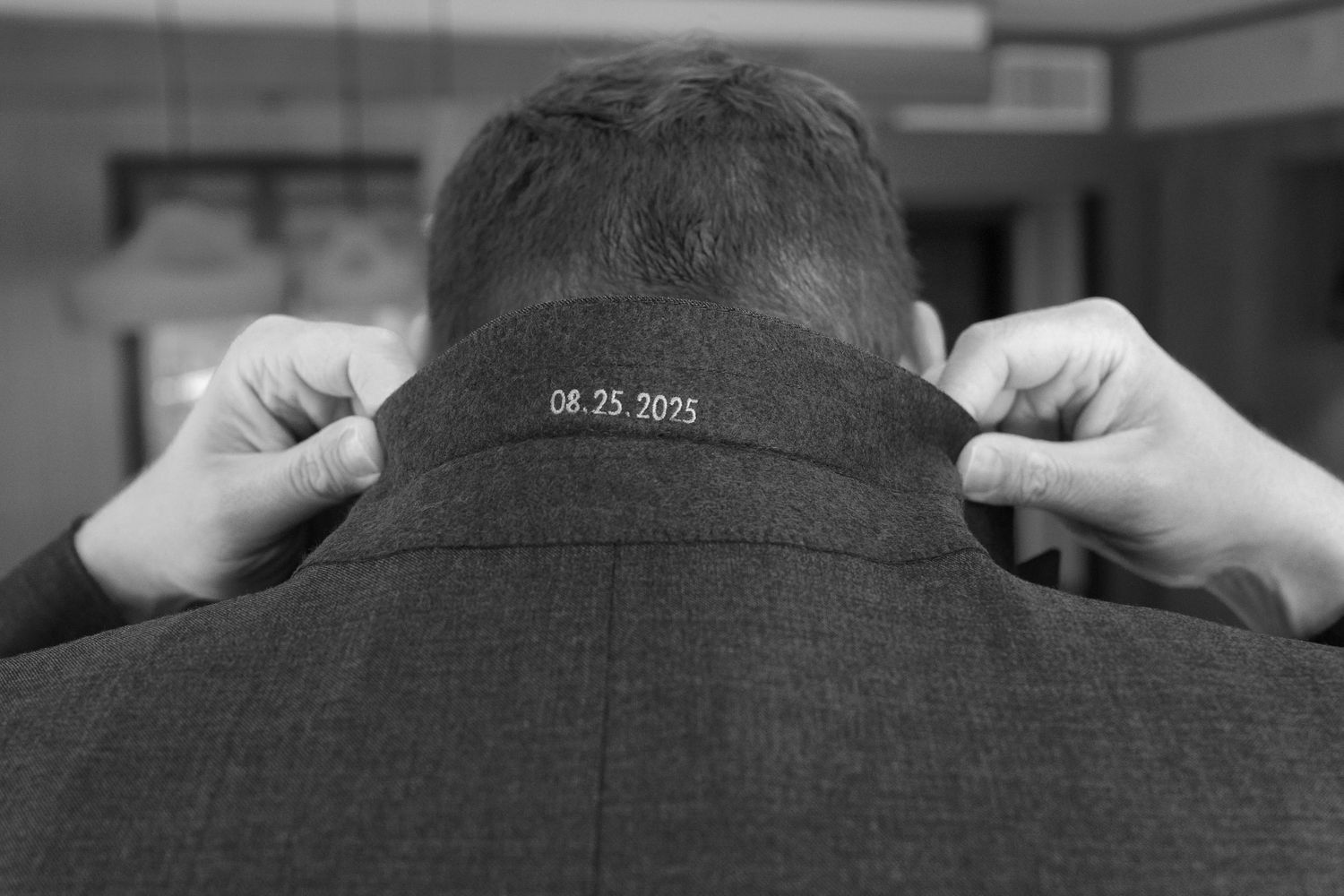 A close-up shot of someone adjusting a dark gray suit collar and tie.
