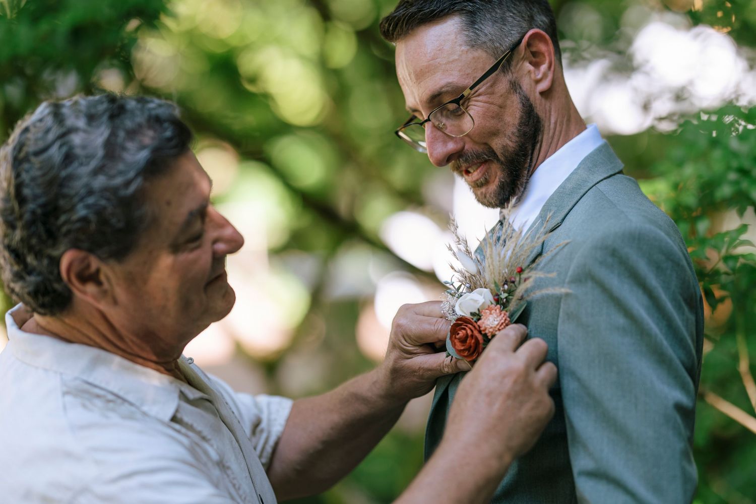 A boutonniere being pinned on a suit jacket during wedding preparations.