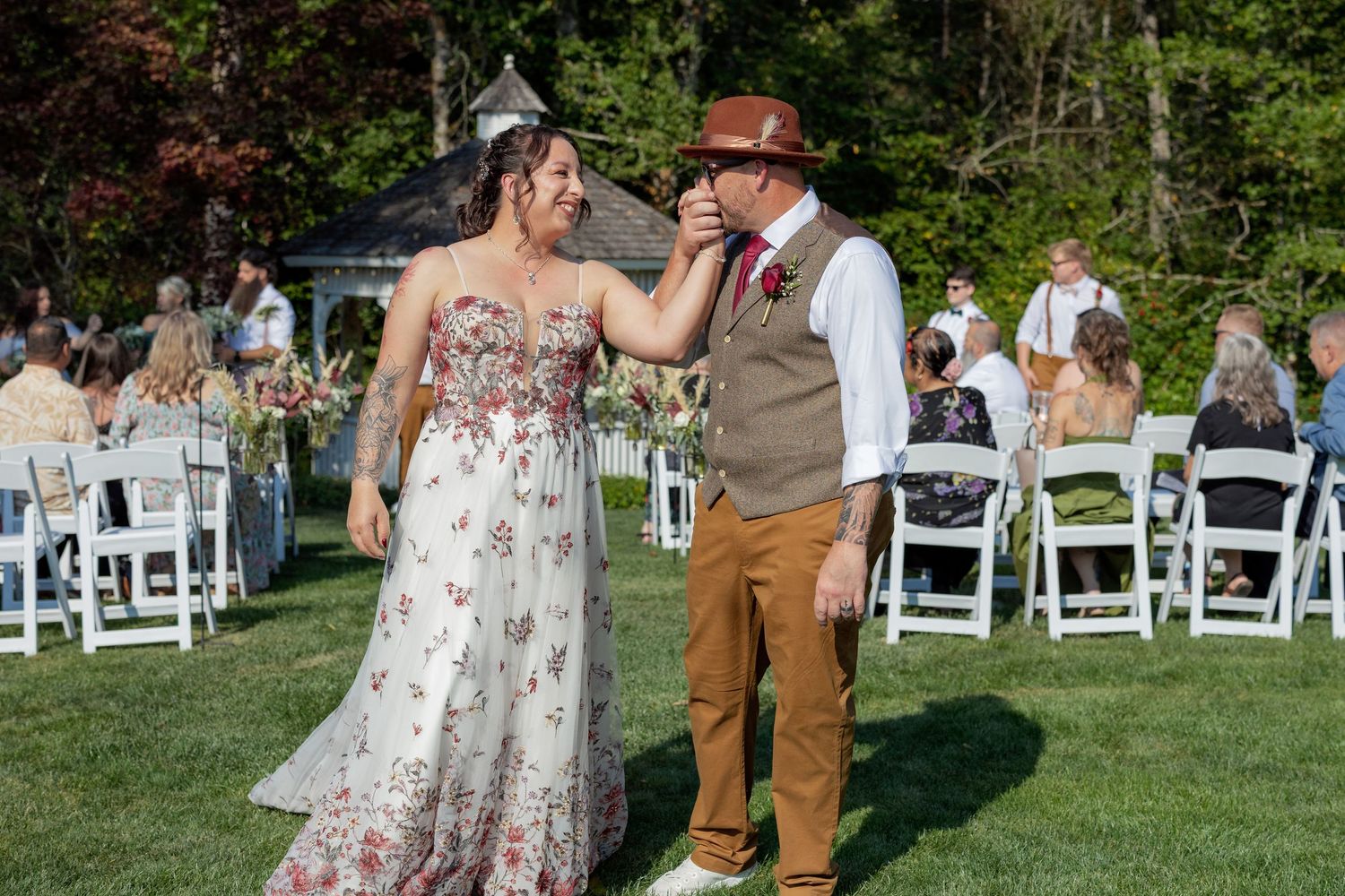 Outdoor wedding ceremony setup with white chairs and natural garden backdrop.