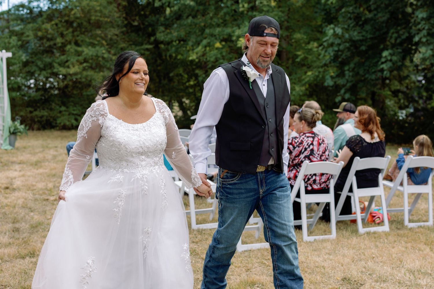 Wedding ceremony setup outdoors with white chairs and mint green fabric decorations.