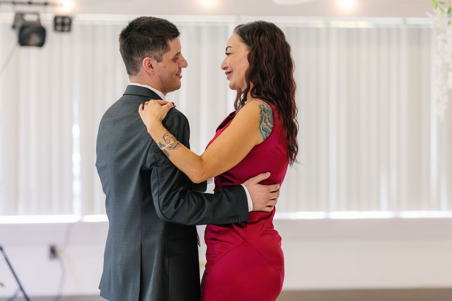 A couple shares an intimate dance moment in formal attire at a wedding reception.