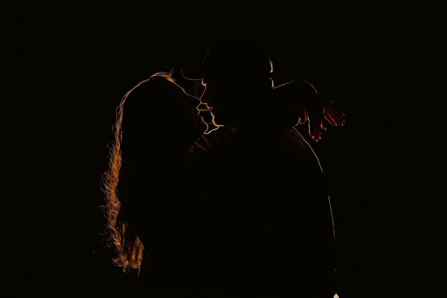 A silhouetted figure stands in a dark room with dramatic rim lighting creating a glowing outline effect.