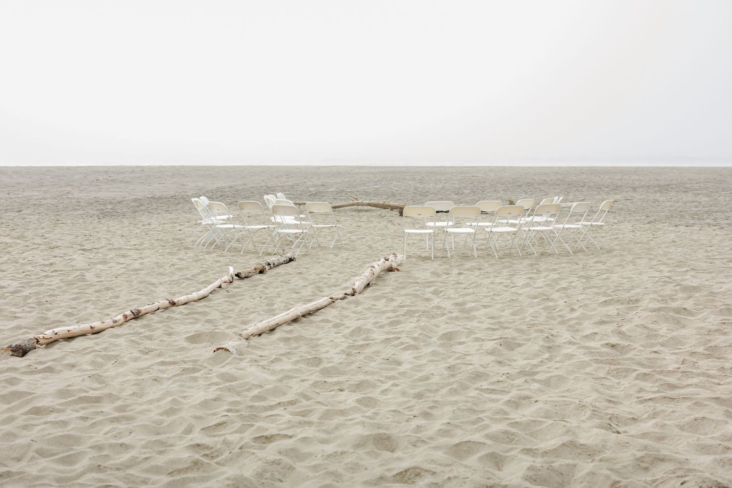 Wooden logs create pathways on a sandy beach with white surf in the background.