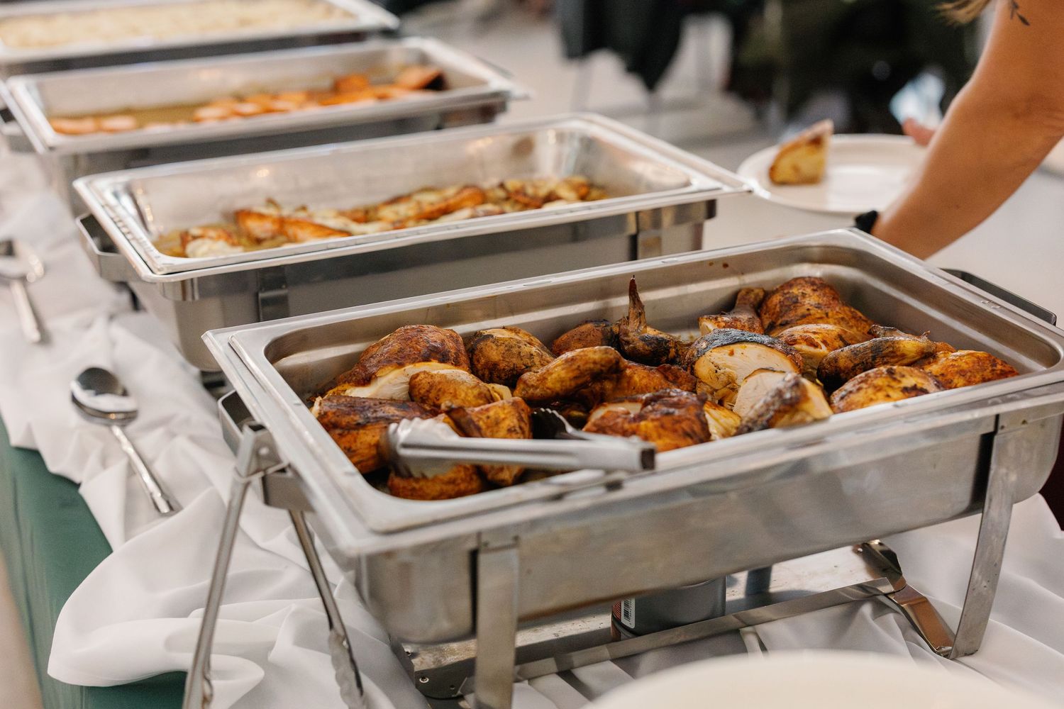 Buffet line of catering chafing dishes filled with food at wedding reception.