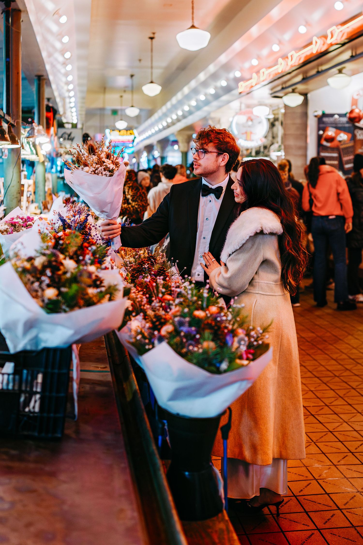 Wedding celebration inside Pike Place Market with colorful floral arrangements and string lights.