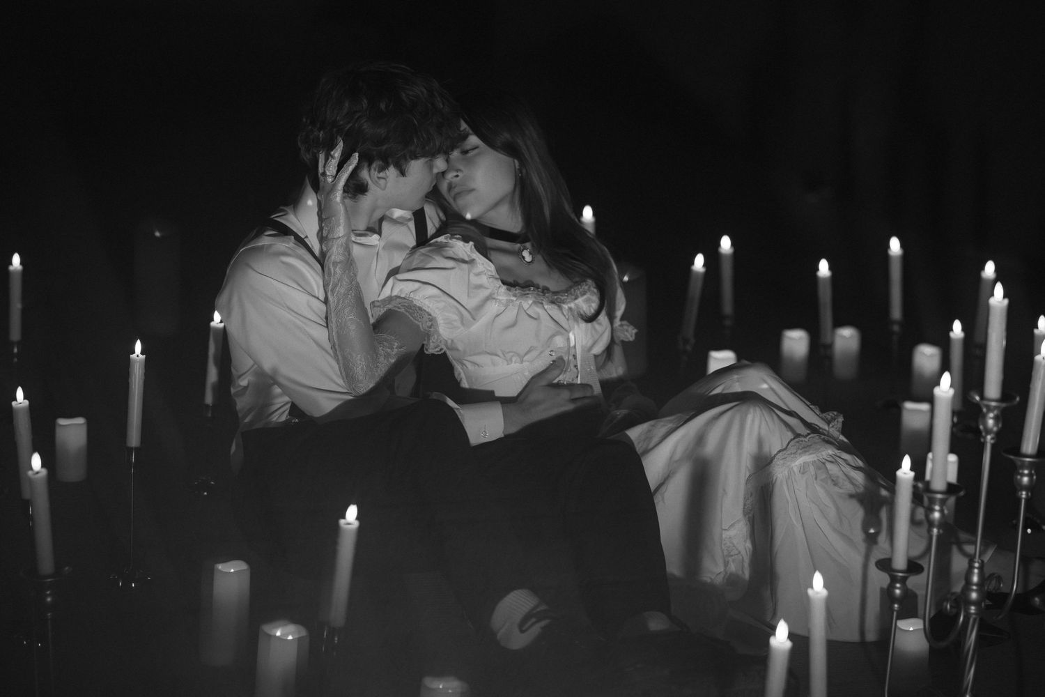 A row of lit candles illuminates a dark room during a candlelight ceremony.
