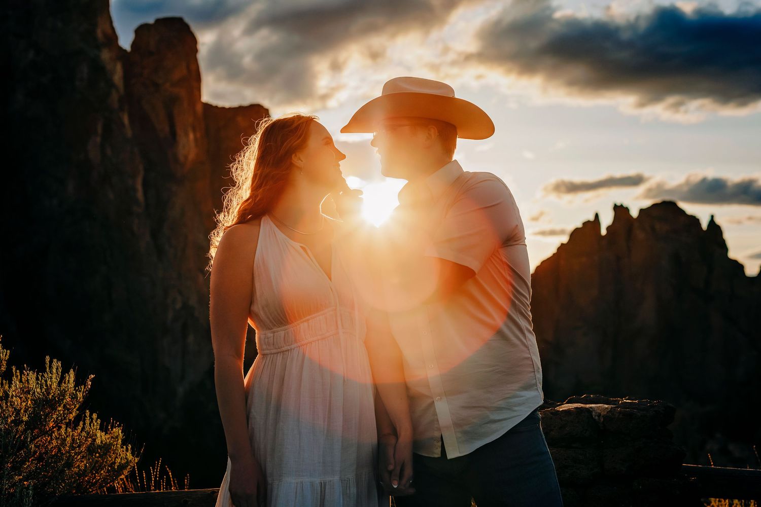 Dramatic sunset silhouettes against rocky cliffs with sunburst through clouds.