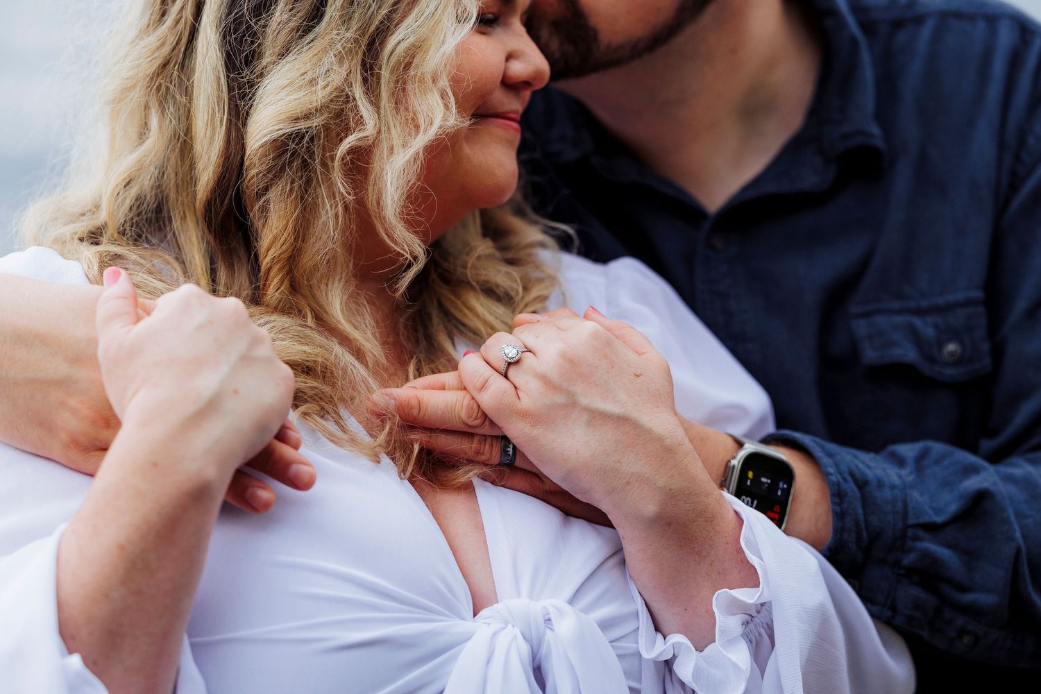 Romantic close-up of couple sharing an intimate moment together, with woman in white top and partner in navy blue.