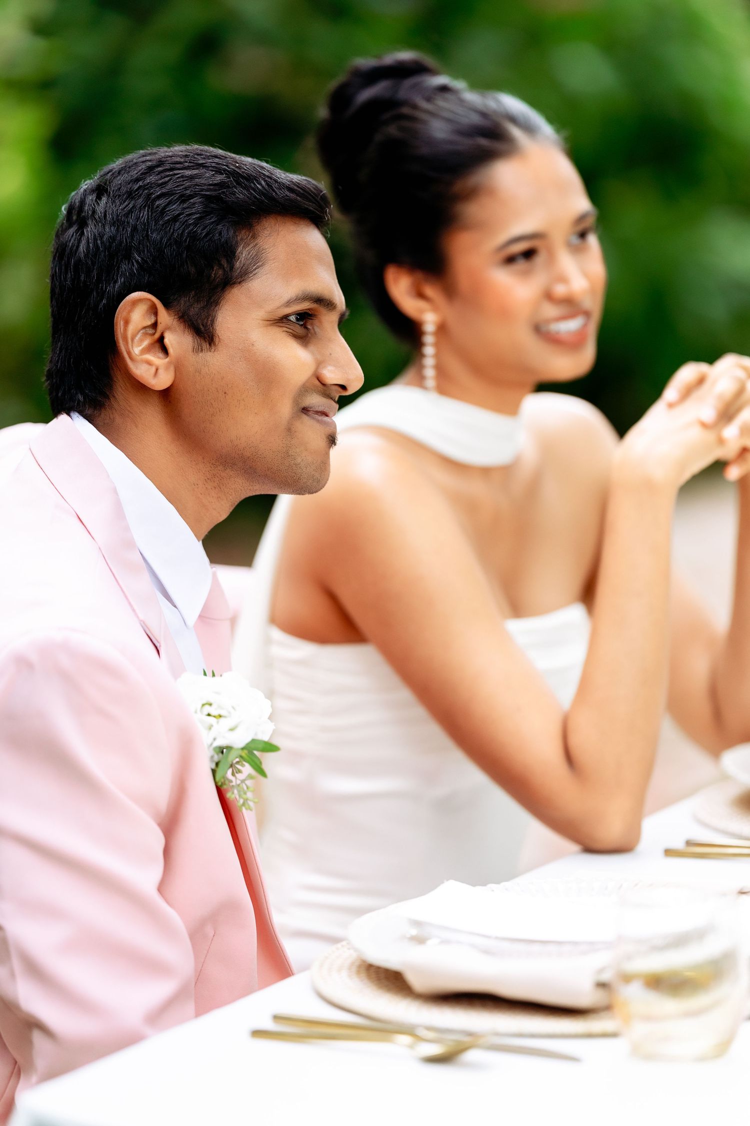 Wedding party guests seated at an elegant outdoor table in white and pink attire.