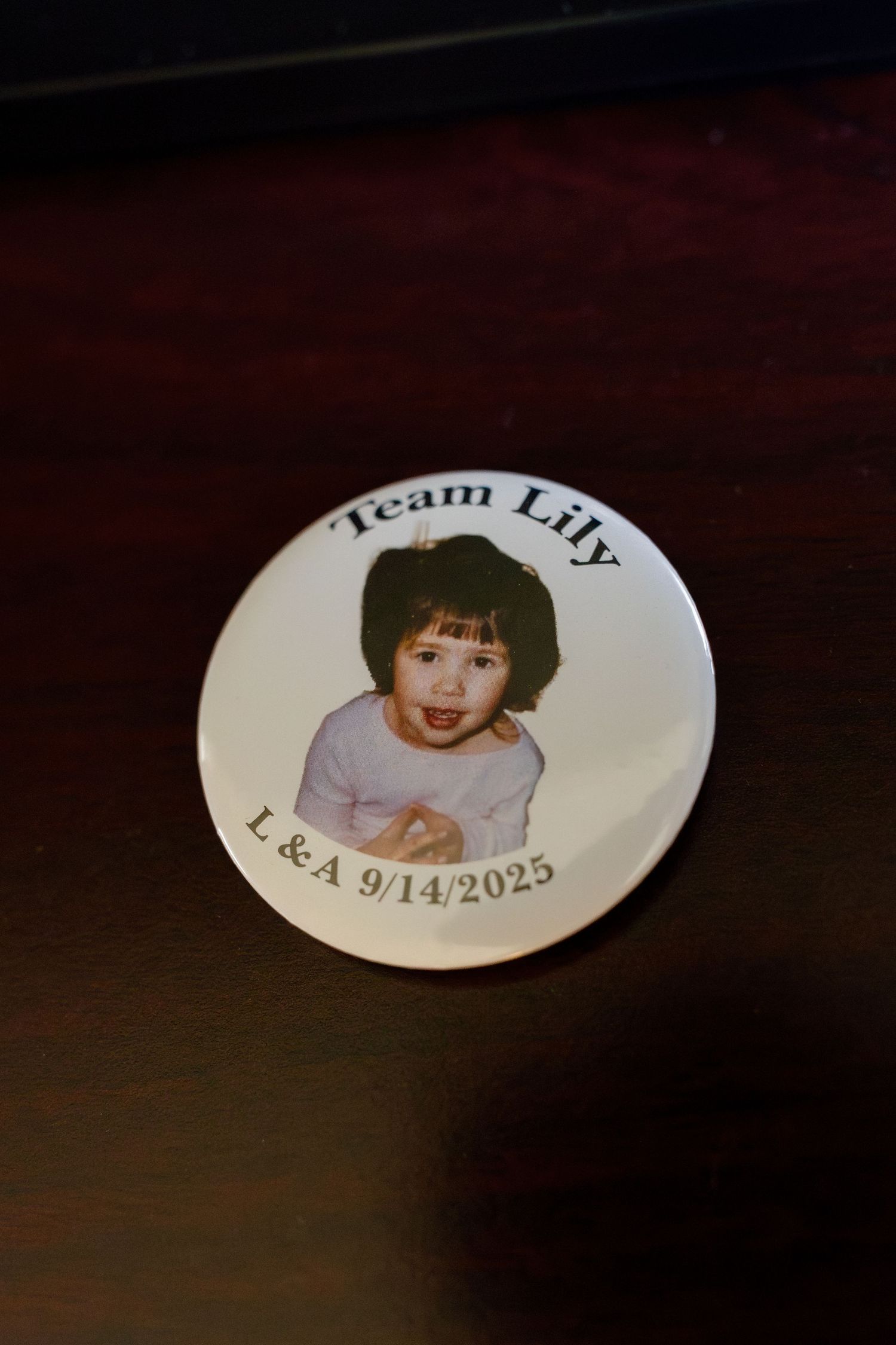 A personalized wedding button or pin with text and a photo against a dark background.