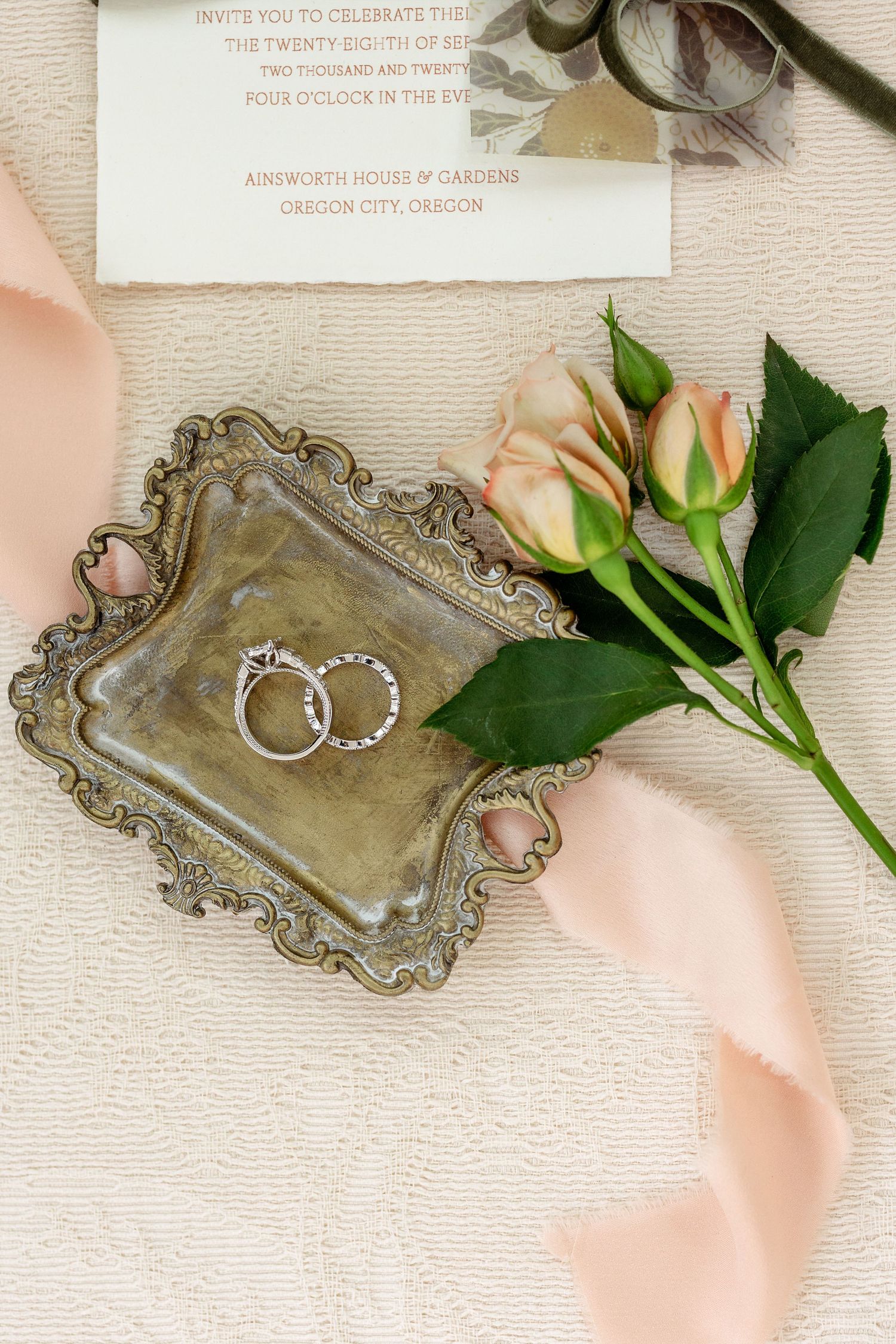 Vintage silver tray with wedding invitation and delicate pink ribbon accent.