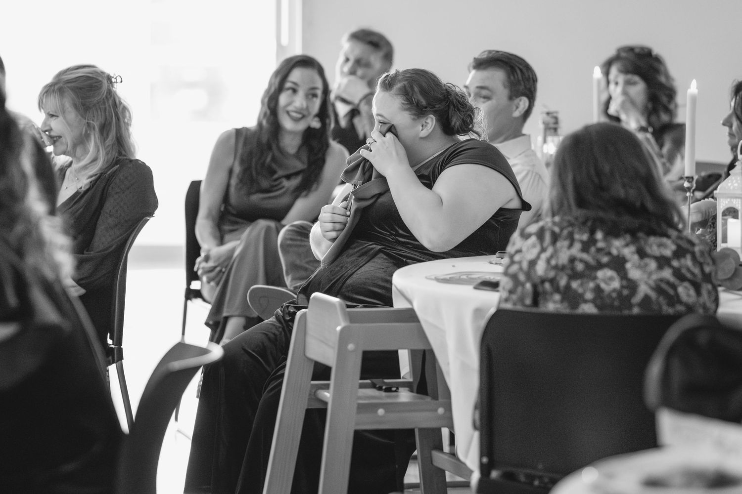 Candid black and white photo of wedding guests smiling and enjoying the celebration.
