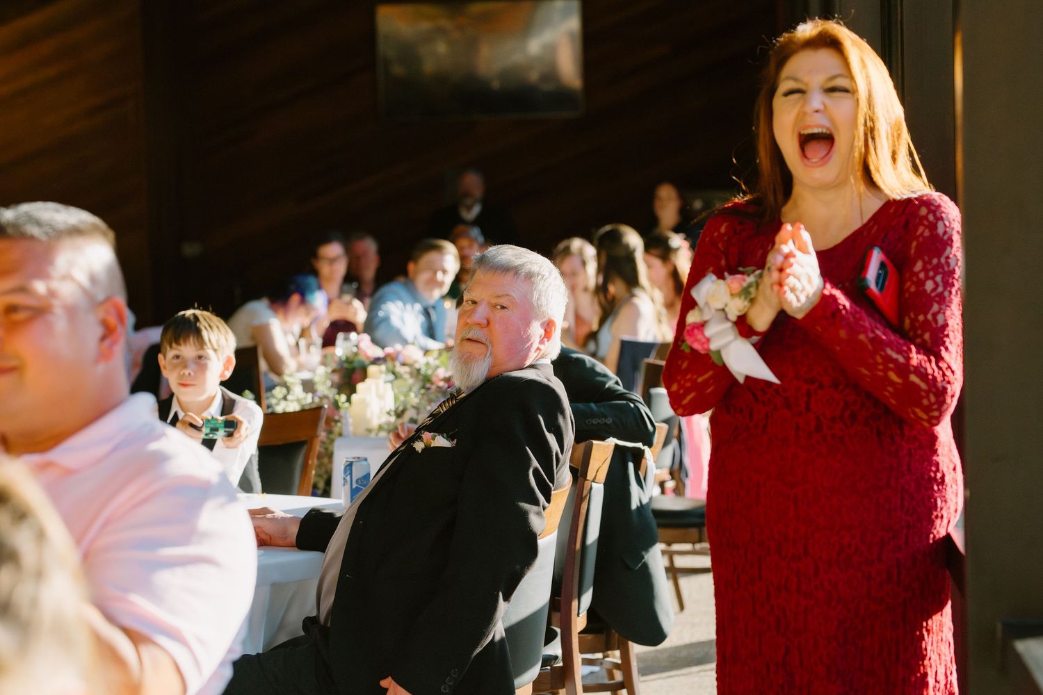 Woman in red sequin dress reacting emotionally during wedding reception speech at venue.