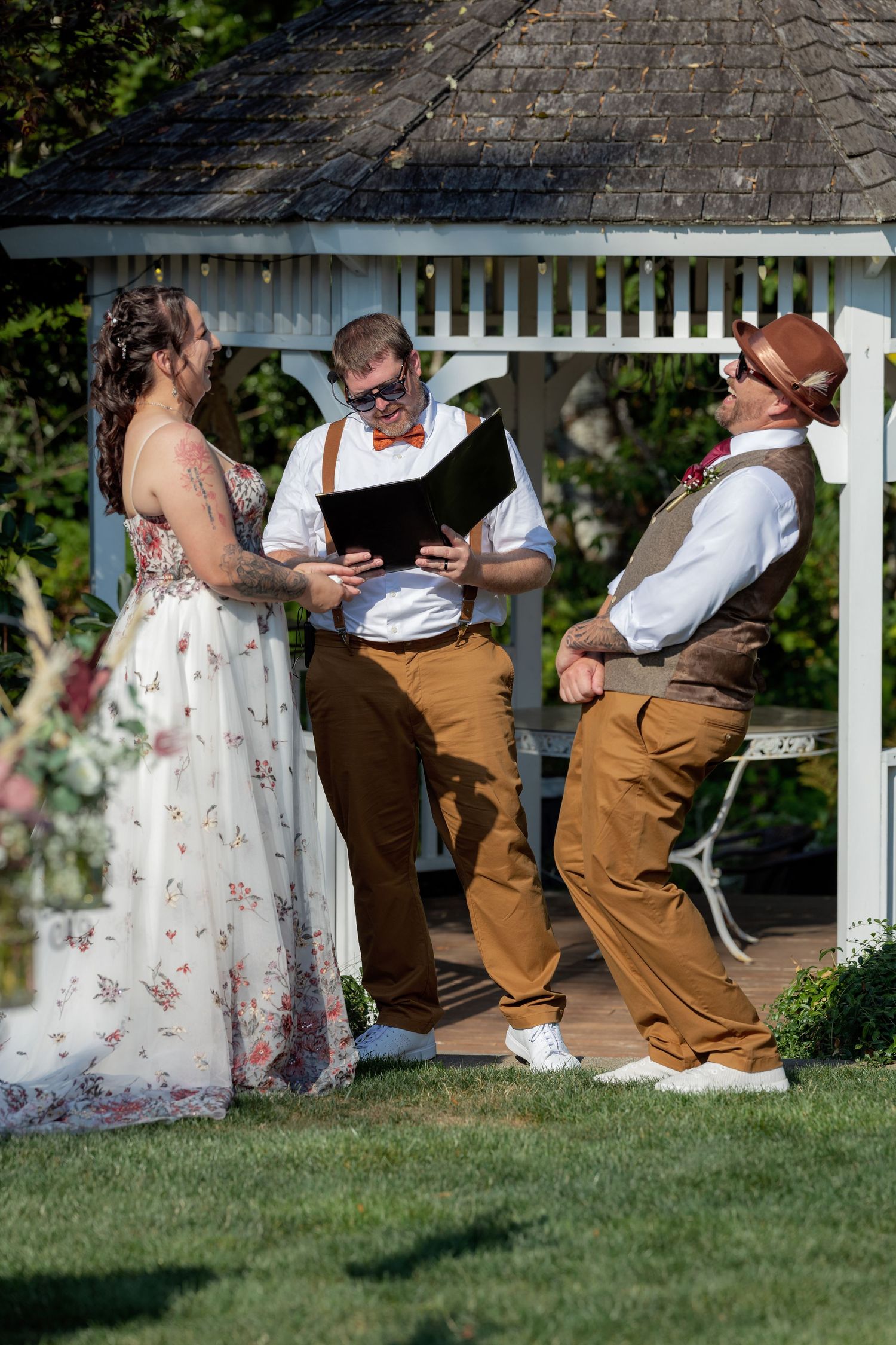 A couple sits together on grass during an outdoor wedding photoshoot.