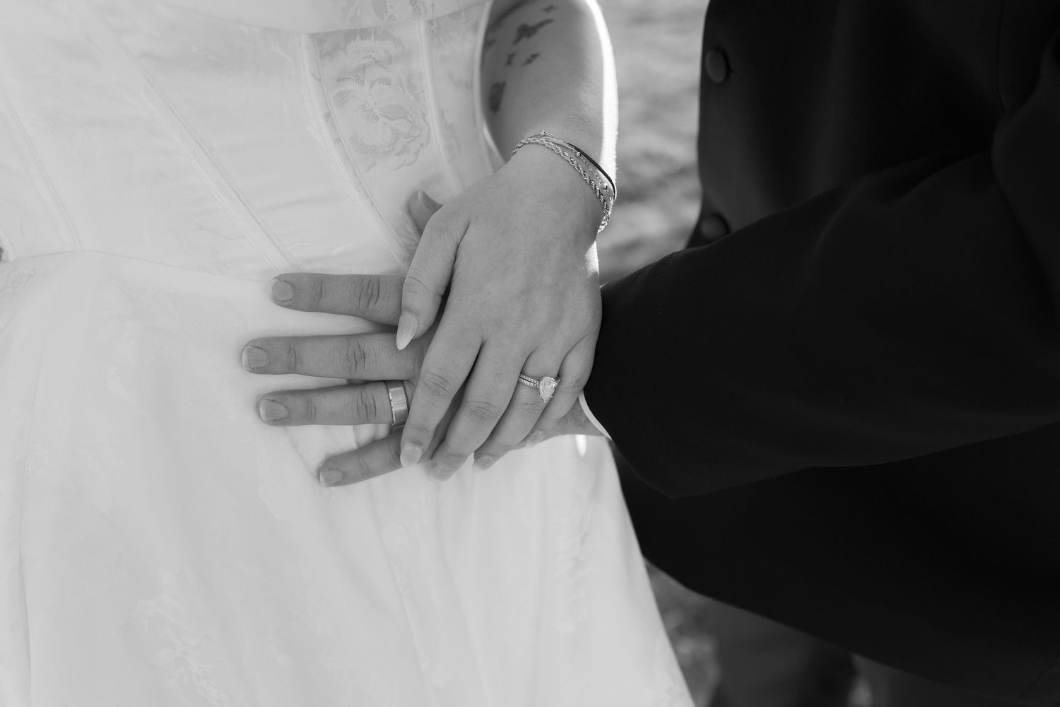Close-up view of hands on a white surface with formal black and white attire visible in the background.
